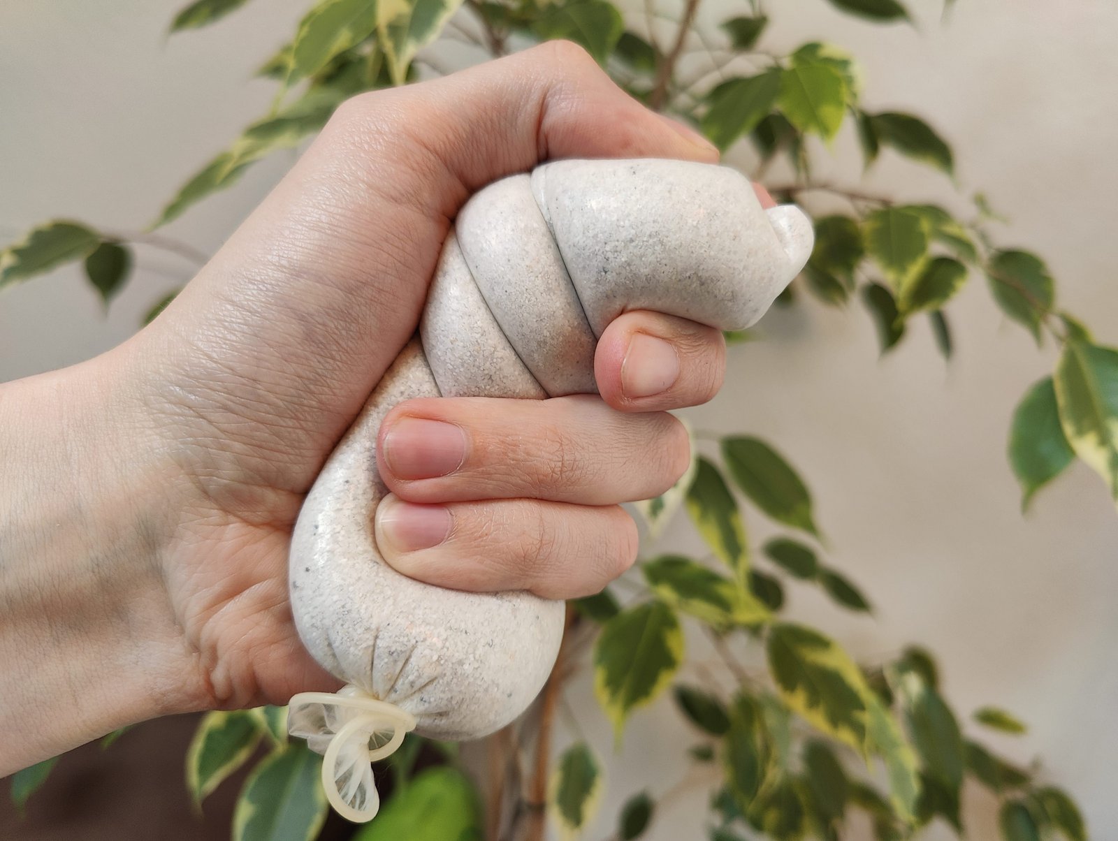 Прострочений презерватив, наповнений піском, у руці людини, яка використовує його як м'яч для розслаблення